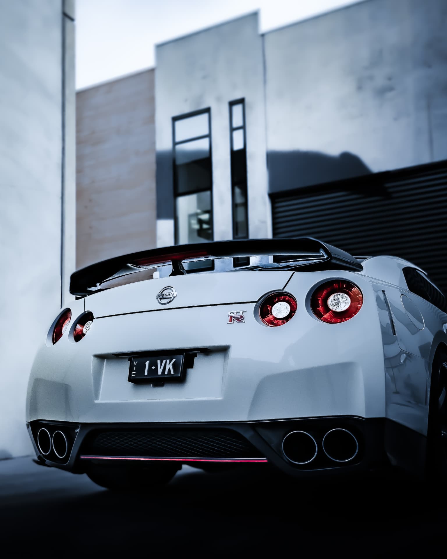 Rear view of a white Nissan GT-R with tail lights lit