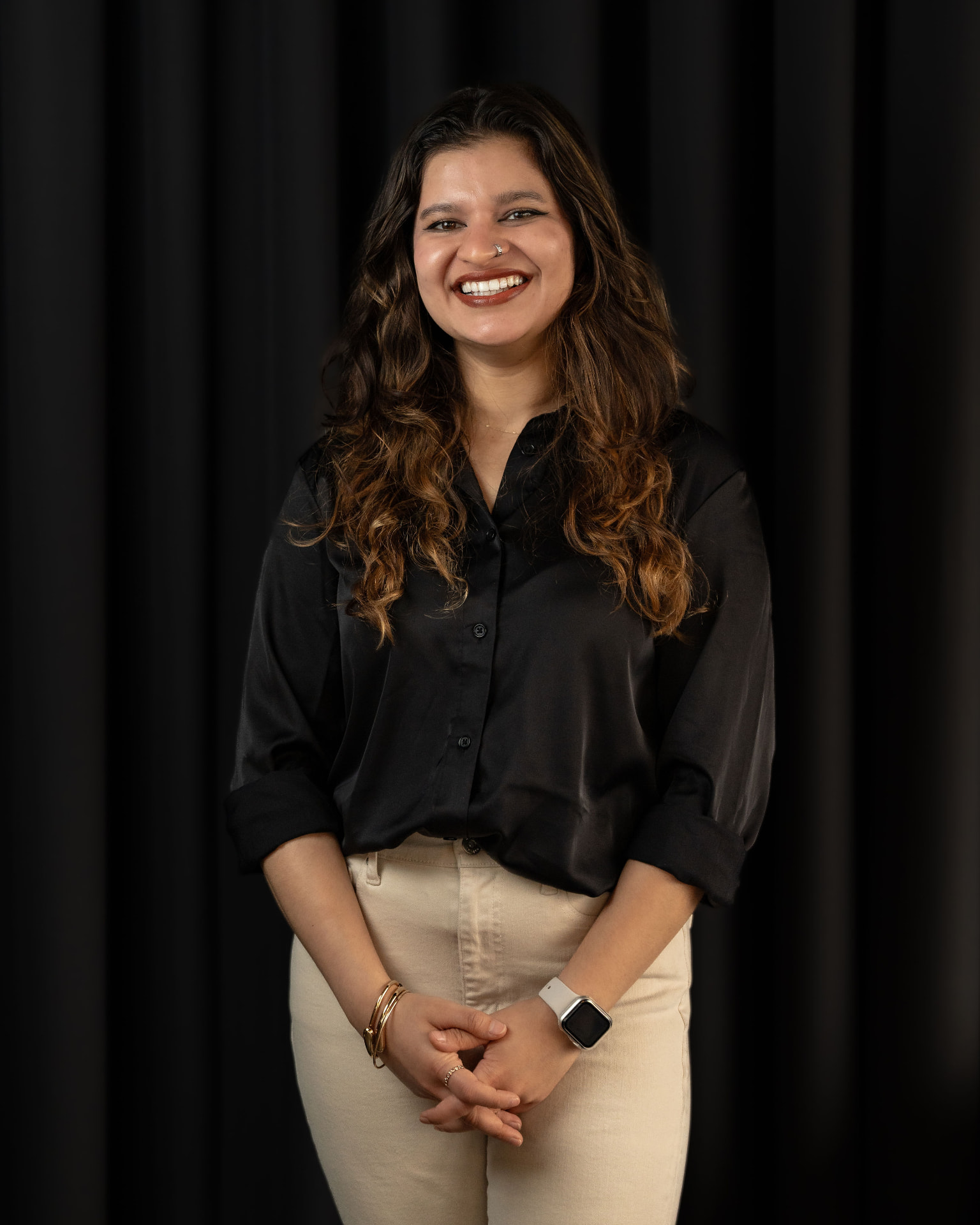 Studio portrait of a woman smiling against a dark background