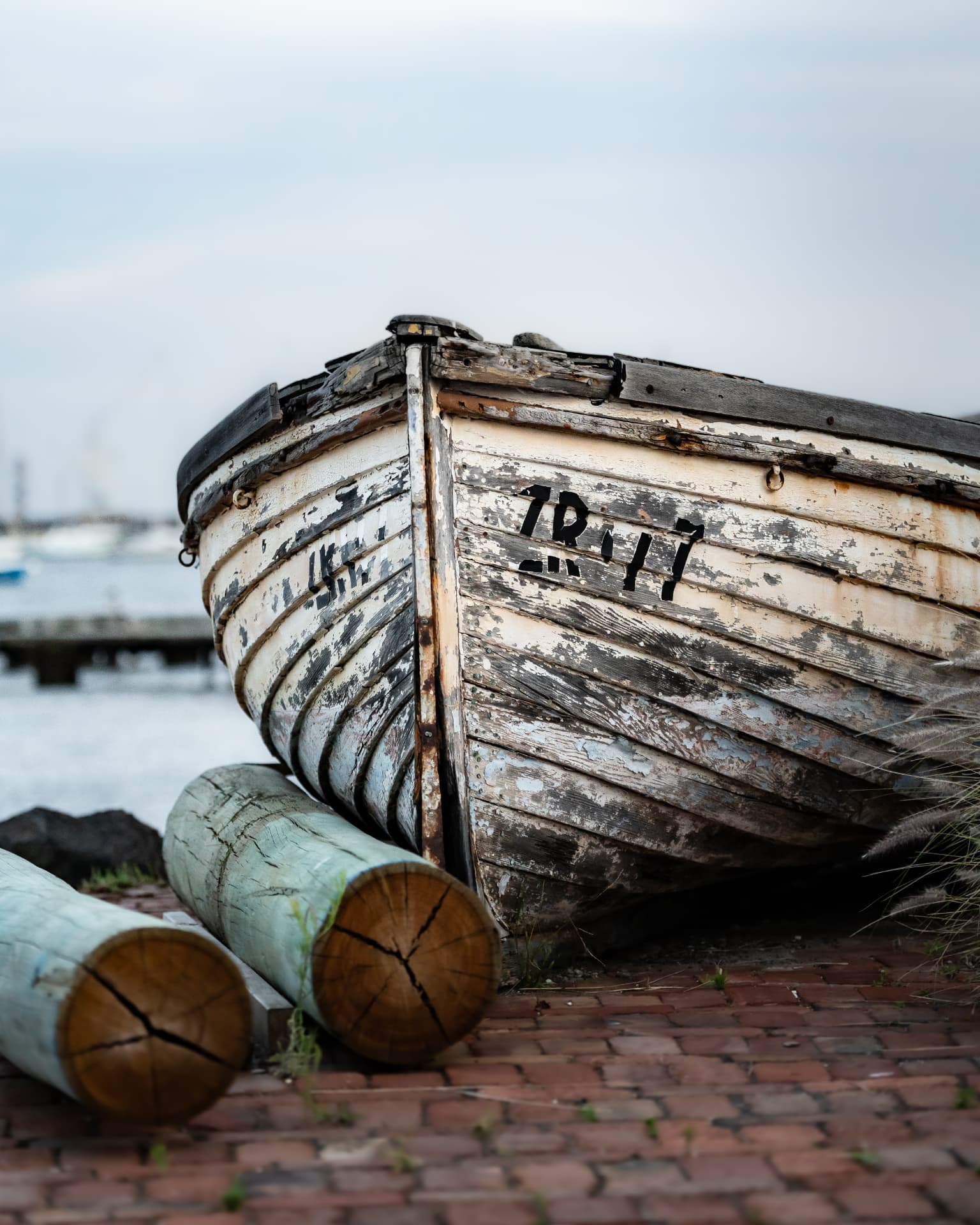 Weathered wooden boat resting on logs beside the bay