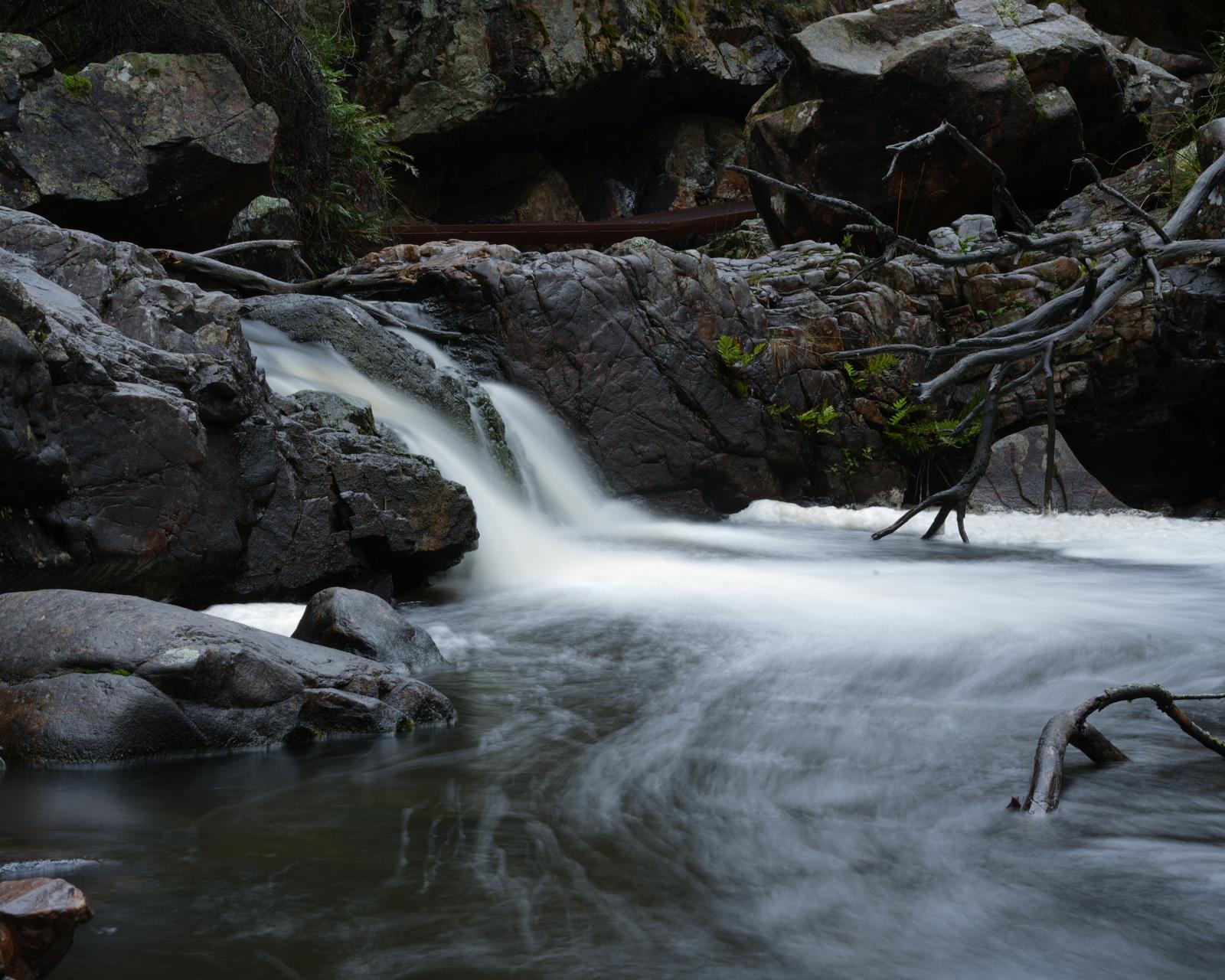 Long-exposure waterfall cascading over dark river rocks