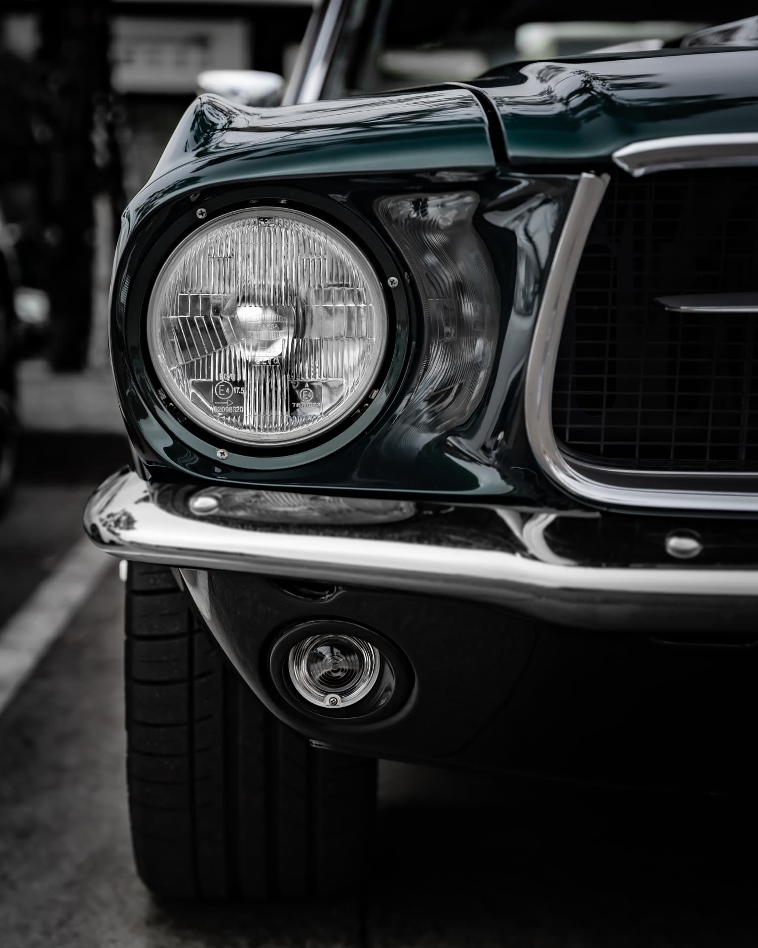 Headlight and chrome detail of a dark green classic Mustang