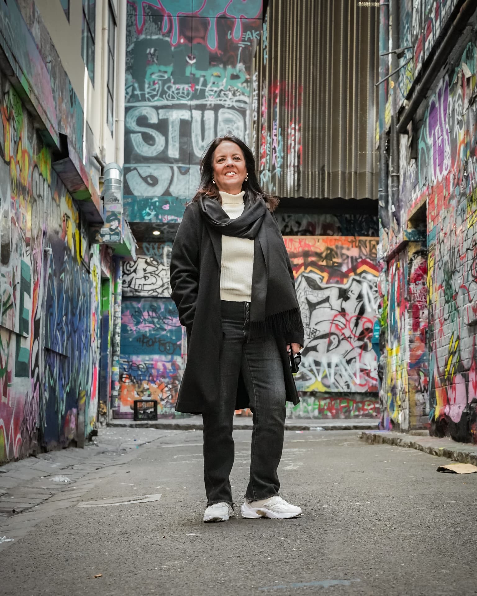 Woman standing in a colourful graffiti-covered Melbourne laneway