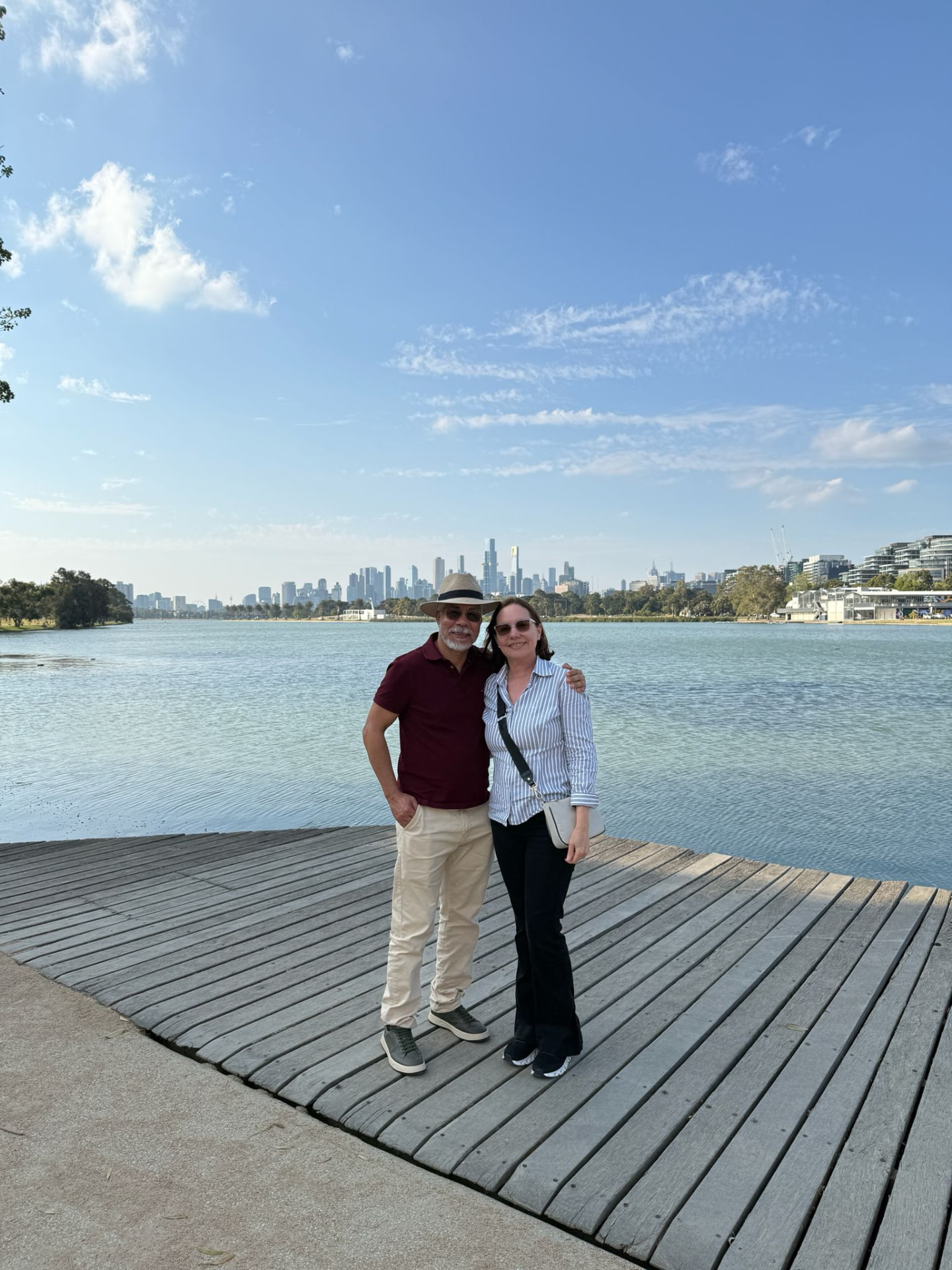 Couple on the Albert Park Lake boardwalk with the Melbourne skyline behind them