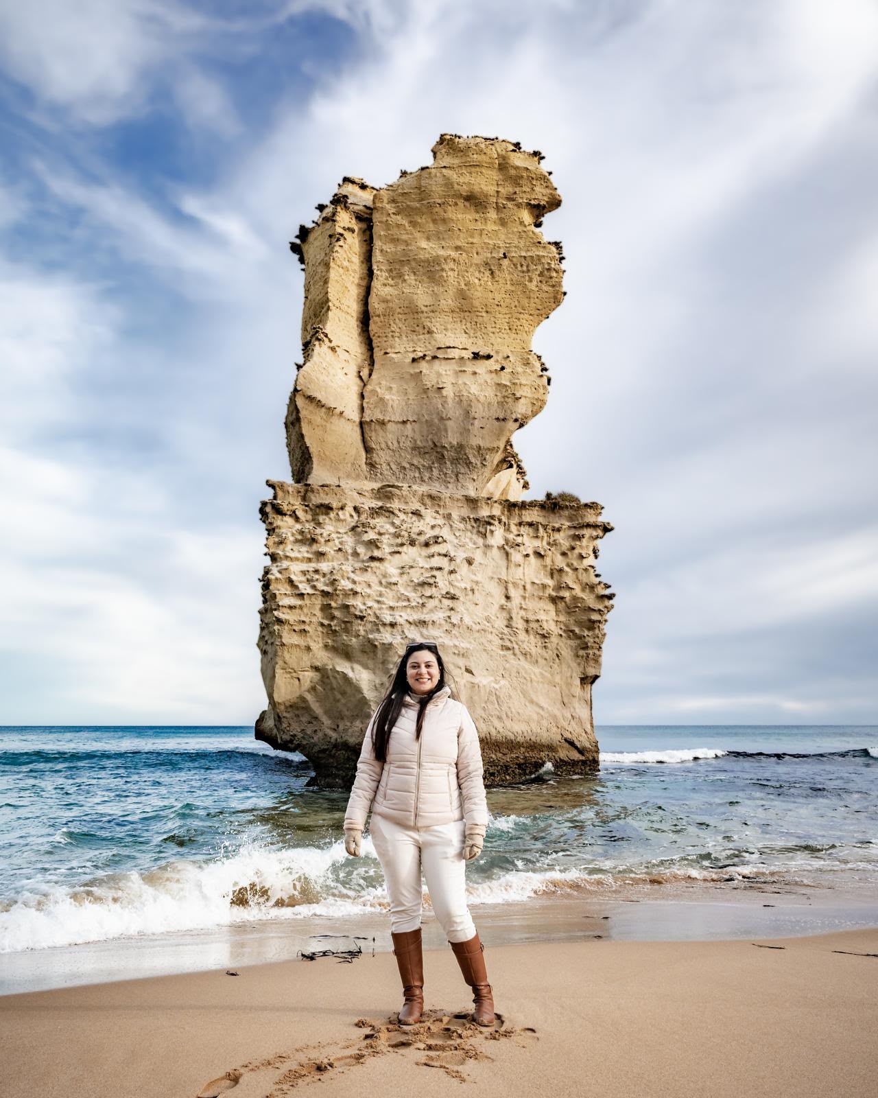 Woman photographed in front of a Twelve Apostles rock stack on the beach