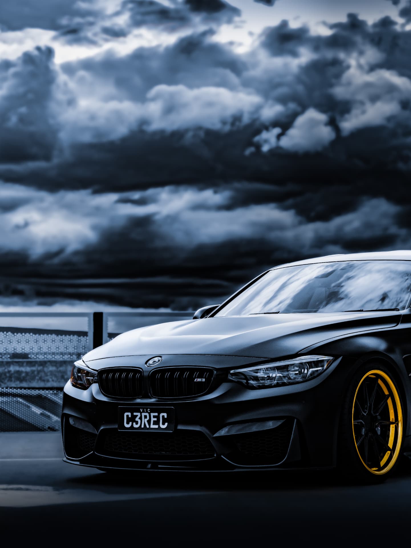 Front three-quarter view of a black BMW M3 with yellow wheels